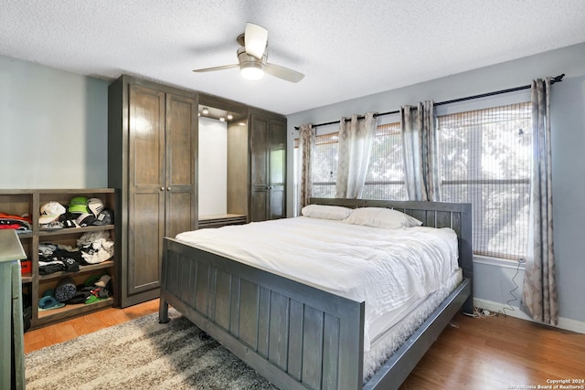 bedroom featuring ceiling fan, light hardwood / wood-style floors, and a textured ceiling