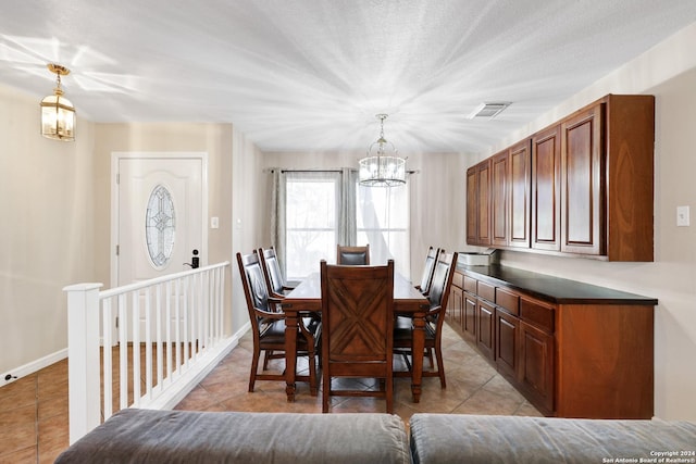 dining room featuring light tile patterned floors, a textured ceiling, and a notable chandelier