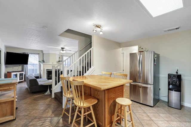 kitchen featuring a breakfast bar area, stainless steel fridge, light tile patterned flooring, and a textured ceiling