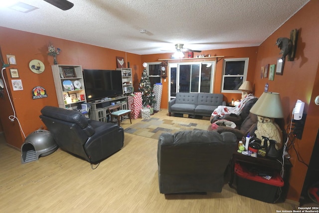 living room featuring ceiling fan, light hardwood / wood-style floors, and a textured ceiling