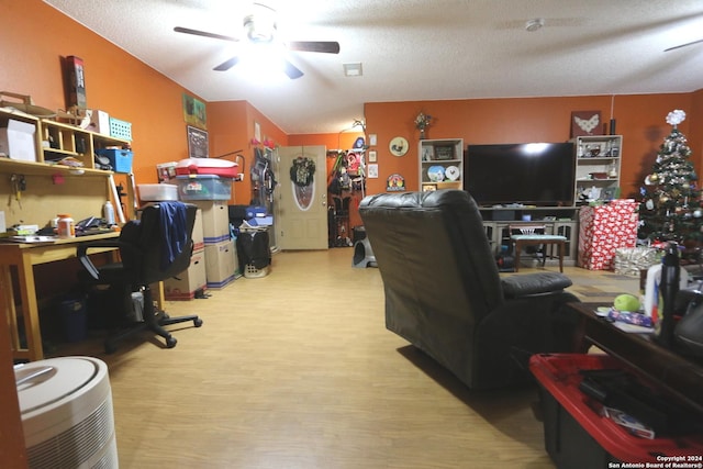 home office with ceiling fan, light hardwood / wood-style flooring, and a textured ceiling