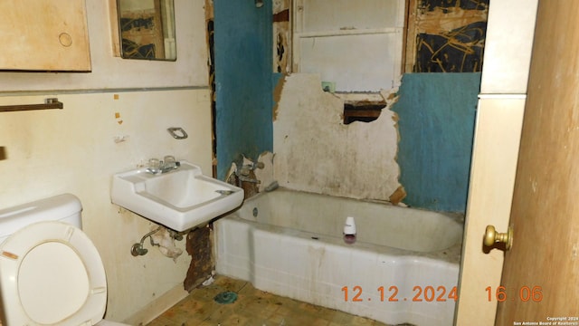 bathroom with a washtub, sink, and toilet