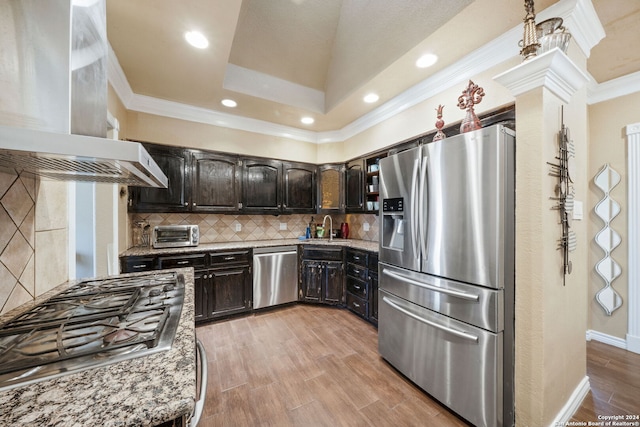 kitchen featuring wall chimney range hood, sink, ornamental molding, dark brown cabinetry, and stainless steel appliances