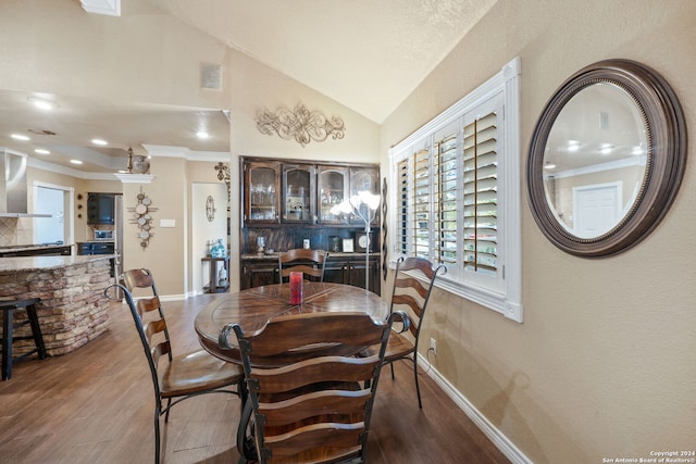 dining room featuring lofted ceiling, crown molding, and dark wood-type flooring