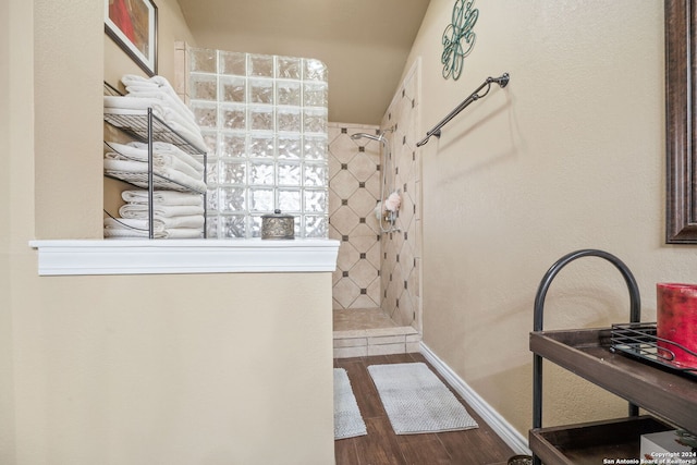 bathroom with wood-type flooring and a tile shower