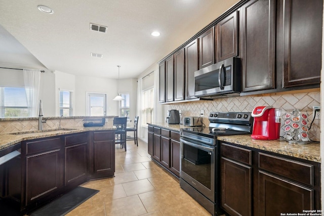 kitchen featuring sink, backsplash, pendant lighting, dark brown cabinets, and appliances with stainless steel finishes