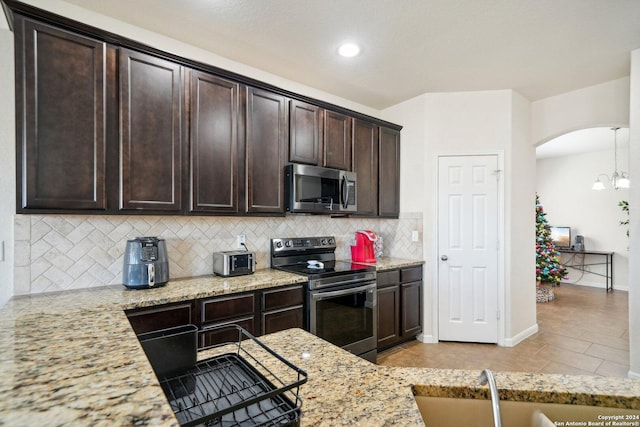 kitchen featuring light stone countertops, dark brown cabinetry, stainless steel appliances, and sink