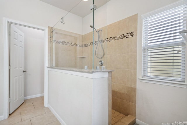 bathroom with tiled shower and tile patterned flooring