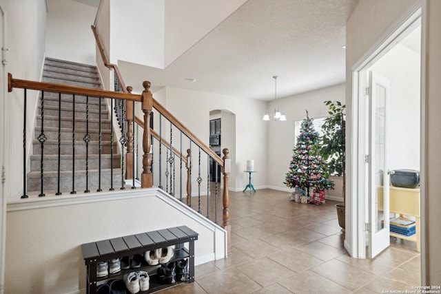 staircase with tile patterned floors and a notable chandelier