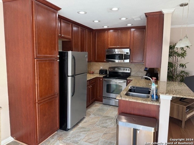 kitchen featuring sink, backsplash, kitchen peninsula, pendant lighting, and appliances with stainless steel finishes