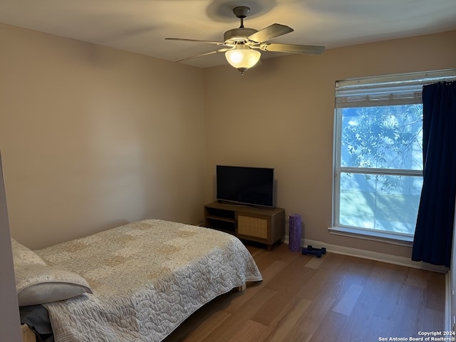 bedroom featuring ceiling fan, wood-type flooring, and multiple windows