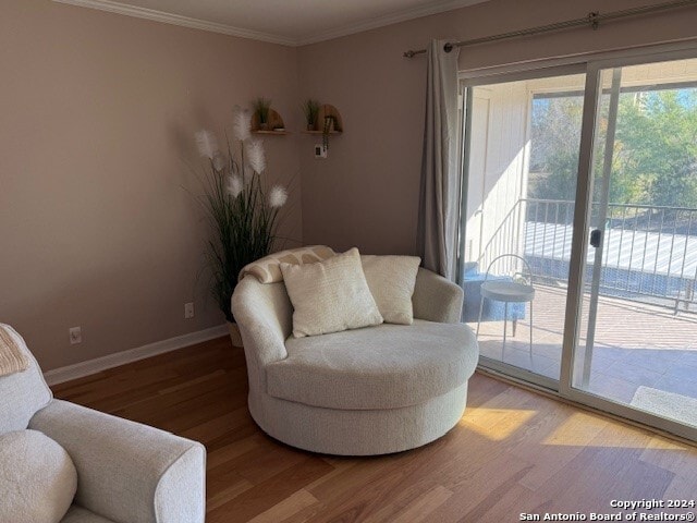 sitting room with wood-type flooring and ornamental molding