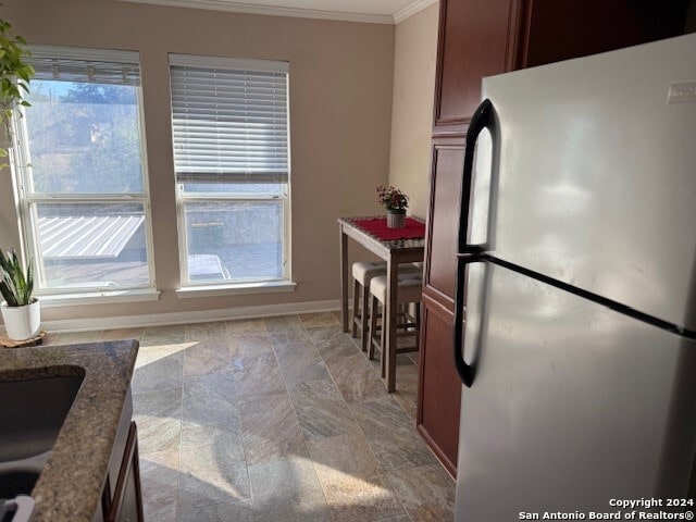 kitchen featuring stainless steel refrigerator, plenty of natural light, and ornamental molding