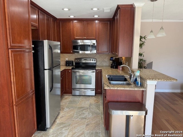 kitchen featuring sink, tasteful backsplash, kitchen peninsula, pendant lighting, and appliances with stainless steel finishes