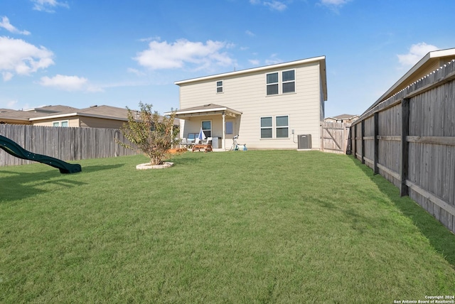 back of property featuring a yard and central AC