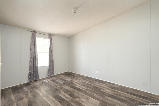 empty room with a textured ceiling and dark hardwood / wood-style flooring