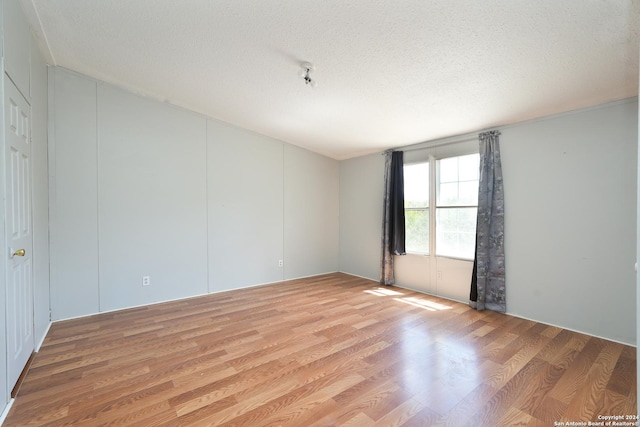 unfurnished room with light hardwood / wood-style floors and a textured ceiling