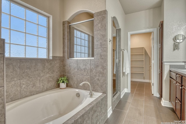 bathroom featuring tile patterned flooring, vanity, independent shower and bath, and a wealth of natural light