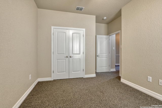 unfurnished bedroom featuring carpet flooring, a textured ceiling, and a closet