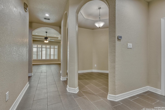 hall featuring ornate columns, a textured ceiling, and light wood-type flooring