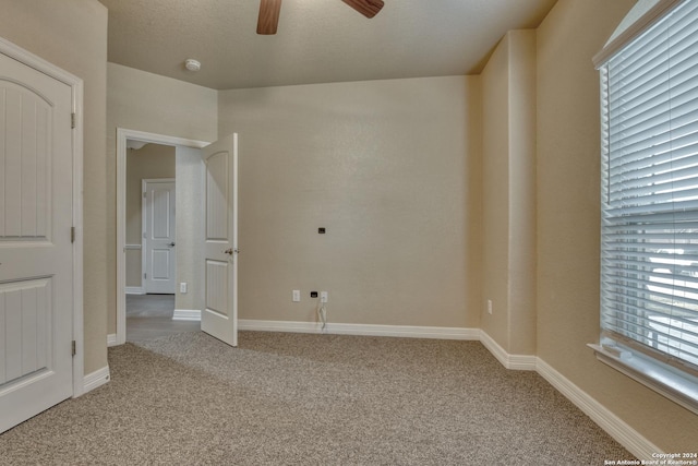 unfurnished bedroom featuring ceiling fan, light colored carpet, and a textured ceiling