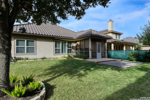 rear view of property featuring a lawn, a sunroom, and a patio