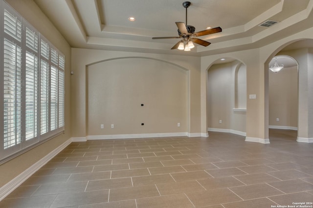 empty room featuring a raised ceiling and ceiling fan