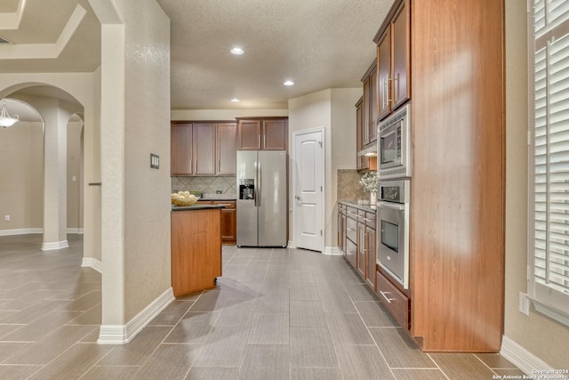 kitchen featuring decorative backsplash, stainless steel appliances, and a textured ceiling