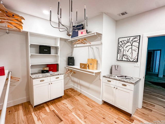 kitchen featuring light hardwood / wood-style floors, light stone countertops, and white cabinetry