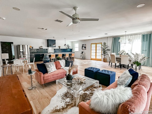 living room with ceiling fan with notable chandelier and light wood-type flooring