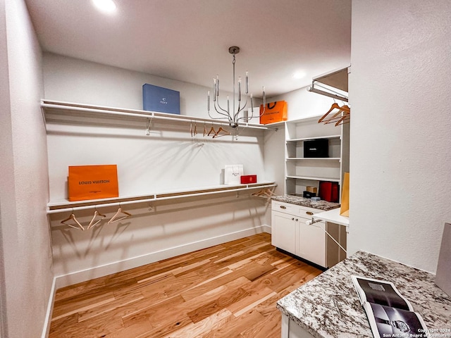 interior space with decorative light fixtures, light hardwood / wood-style floors, light stone counters, and white cabinetry