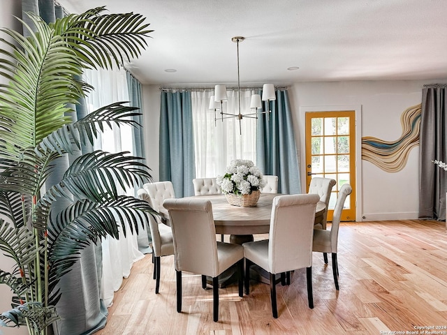 dining space with light hardwood / wood-style flooring and a notable chandelier