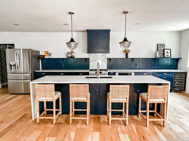 kitchen featuring a breakfast bar, an island with sink, stainless steel refrigerator with ice dispenser, and light hardwood / wood-style flooring