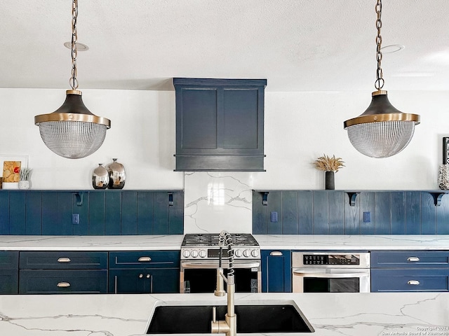 kitchen with appliances with stainless steel finishes, blue cabinets, and hanging light fixtures