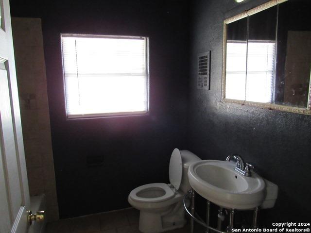 bathroom with tile patterned floors, a tub to relax in, toilet, and sink