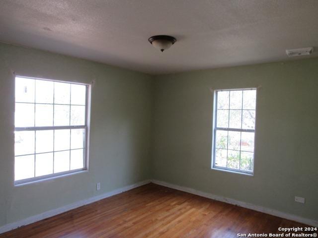 spare room featuring wood-type flooring and a textured ceiling