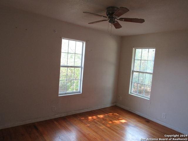 spare room with ceiling fan, hardwood / wood-style floors, and a healthy amount of sunlight