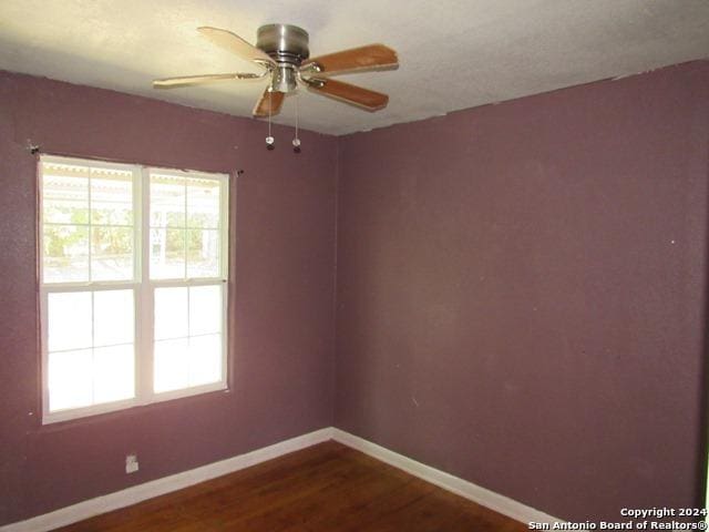 unfurnished room with ceiling fan and dark wood-type flooring