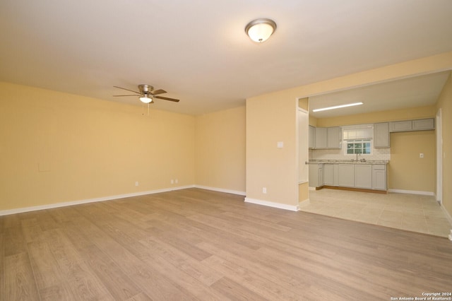 unfurnished living room featuring ceiling fan and light wood-type flooring