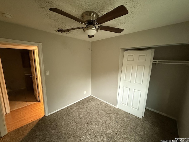 unfurnished bedroom featuring dark colored carpet, ceiling fan, a textured ceiling, and a closet