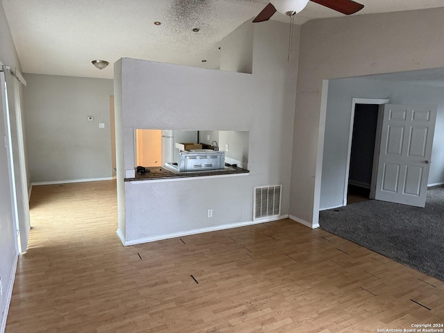 unfurnished living room featuring ceiling fan, a textured ceiling, and light hardwood / wood-style flooring