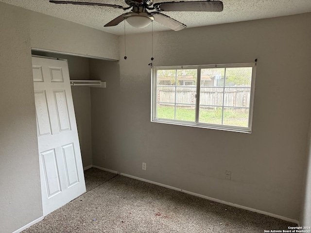 unfurnished bedroom with a textured ceiling, a closet, ceiling fan, and carpet floors