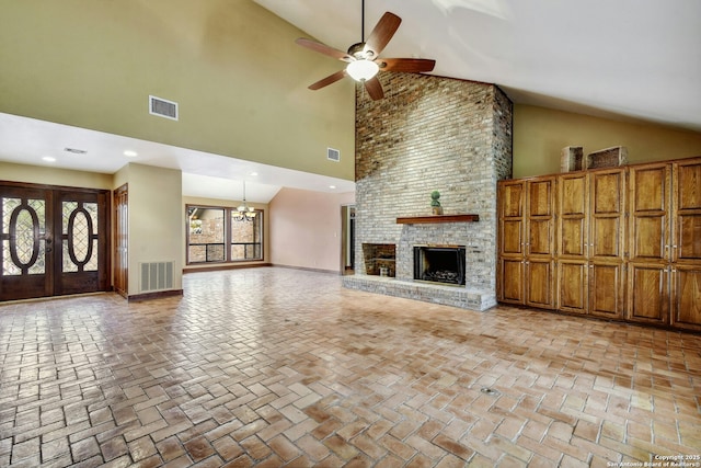 unfurnished living room featuring ceiling fan with notable chandelier, a fireplace, high vaulted ceiling, and french doors