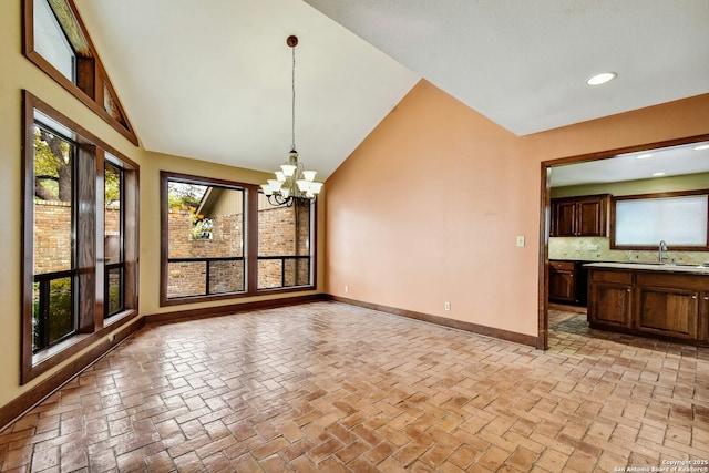 unfurnished dining area featuring sink, an inviting chandelier, and vaulted ceiling