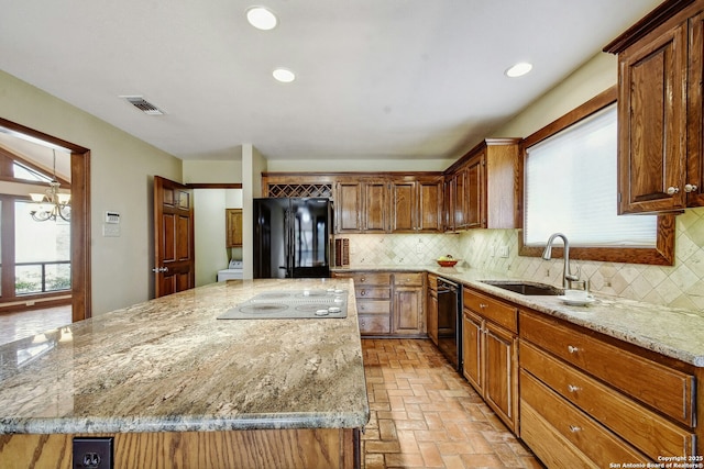 kitchen with sink, an inviting chandelier, light stone counters, tasteful backsplash, and black appliances