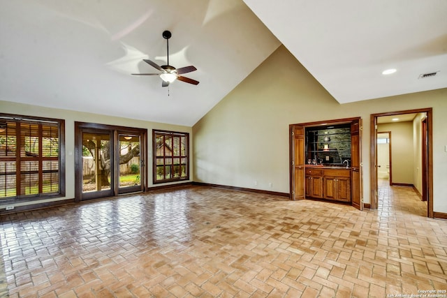 unfurnished living room featuring high vaulted ceiling and ceiling fan