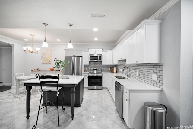 kitchen featuring white cabinets, sink, hanging light fixtures, ornamental molding, and stainless steel appliances