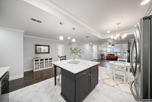 kitchen featuring stainless steel fridge, light hardwood / wood-style floors, a kitchen island, ceiling fan with notable chandelier, and ornamental molding