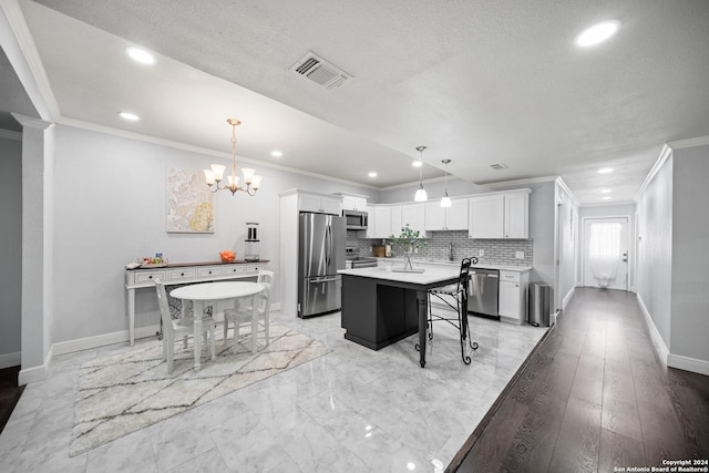 kitchen with appliances with stainless steel finishes, a center island, decorative light fixtures, and white cabinetry