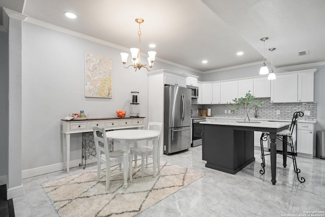 kitchen featuring hanging light fixtures, white cabinets, appliances with stainless steel finishes, a kitchen island, and ornamental molding